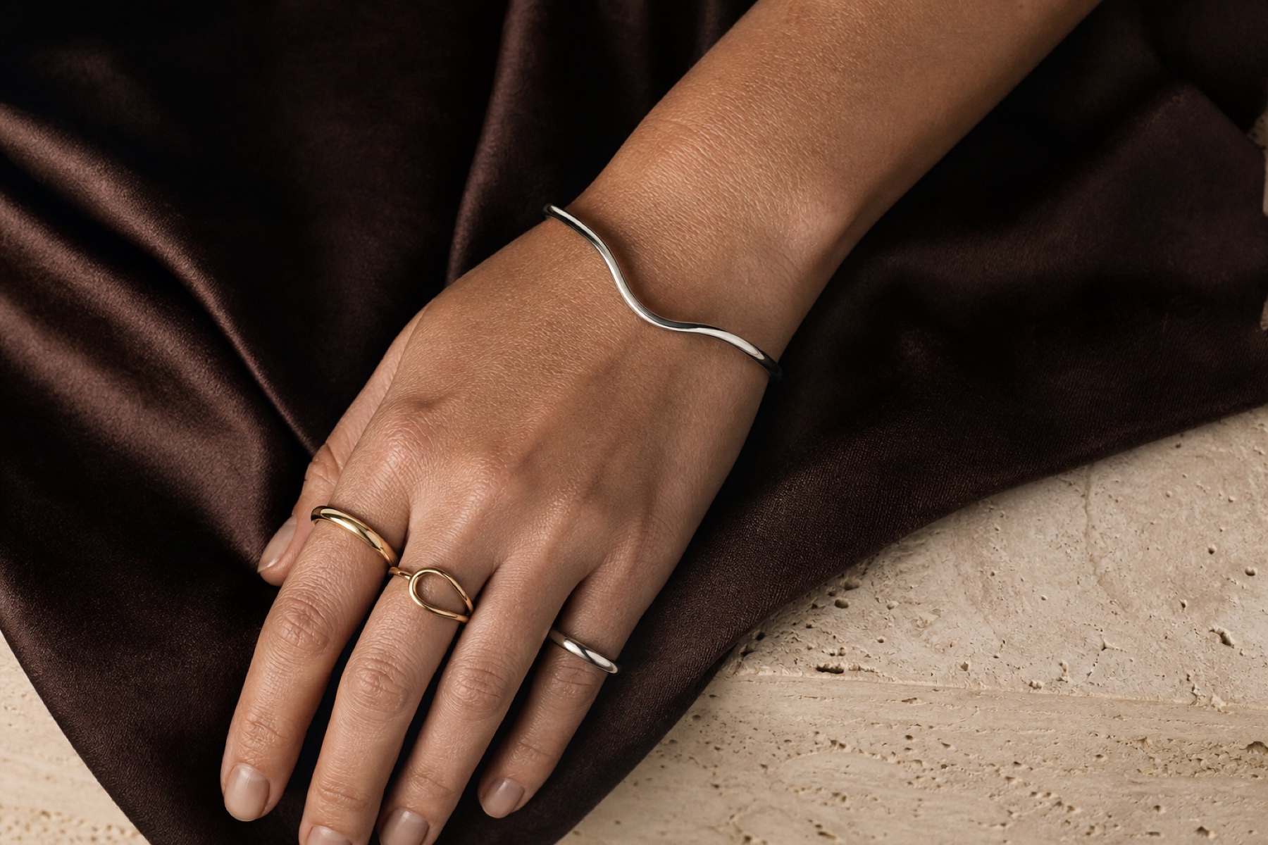 A considered selection of jewelry arranged on warm stone