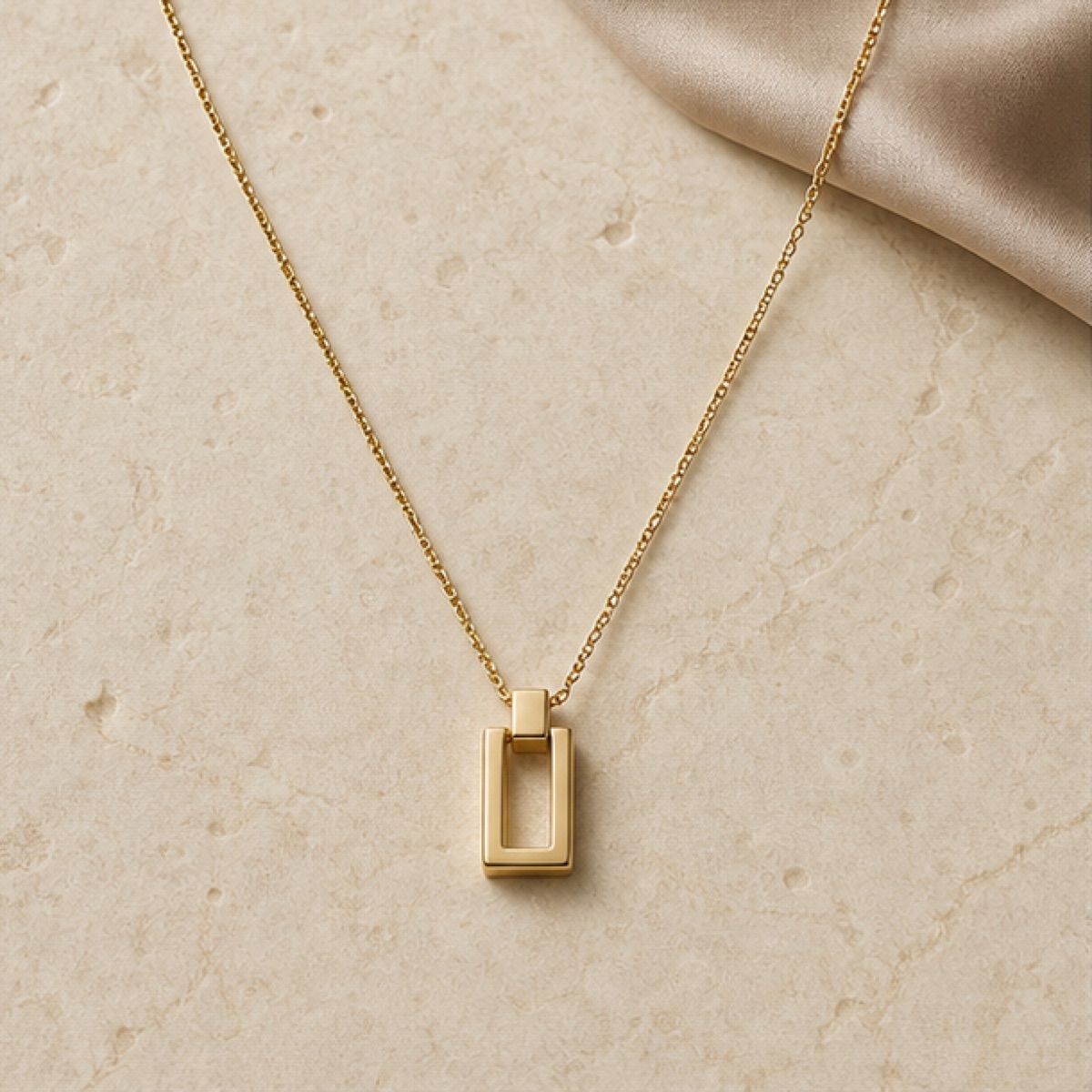A slim pendant resting on warm grey stone